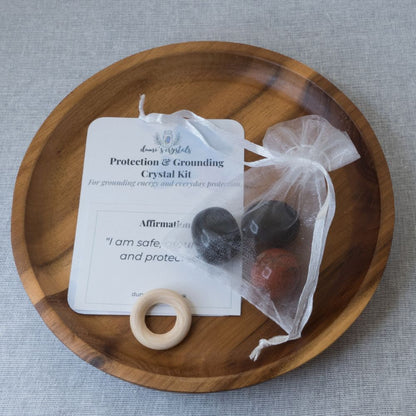 Crystal kit with stones, wooden ring, and card on a wooden tray