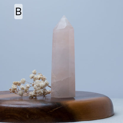Crystal obelisk on a wooden base with dried flowers against a light blue background