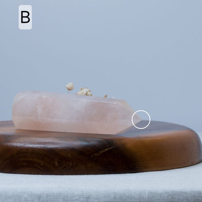 rose quartz tower on a wooden plate with a gray background