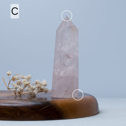 rose quartz Crystal tower on a wooden base with a light blue background