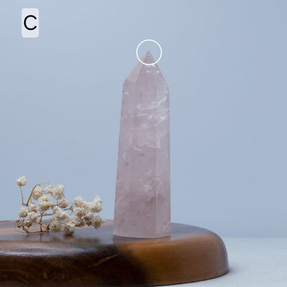 Rose quartz crystal tower on a wooden base with a light blue background