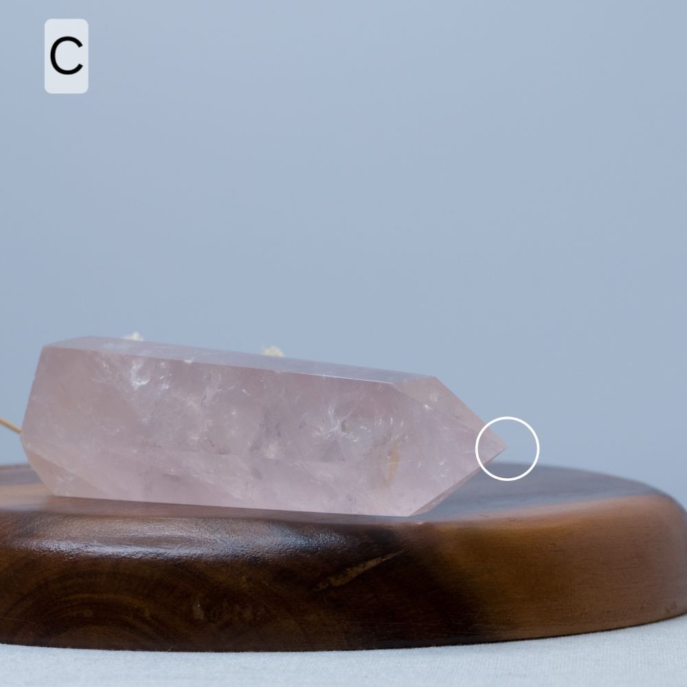 Rose quartz crystal tower on a wooden plate with a gray background