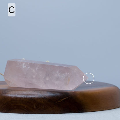 Rose quartz crystal tower on a wooden plate with a gray background