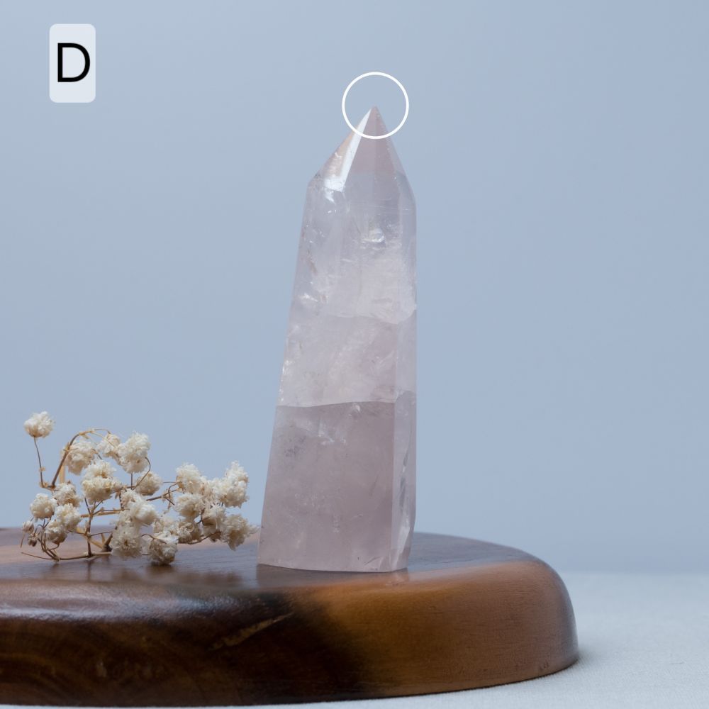 Rose quartz Crystal tower on a wooden base with a light blue background