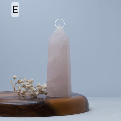 Rose quartz crystal tower on a wooden base with a light blue background
