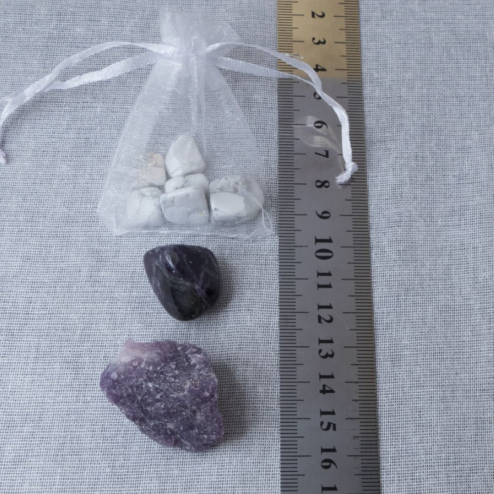 three crystal stones on a white surface with a  ruler for scale.