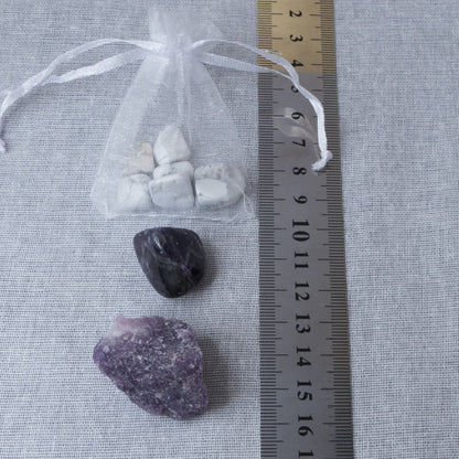 three crystal stones on a white surface with a  ruler for scale.
