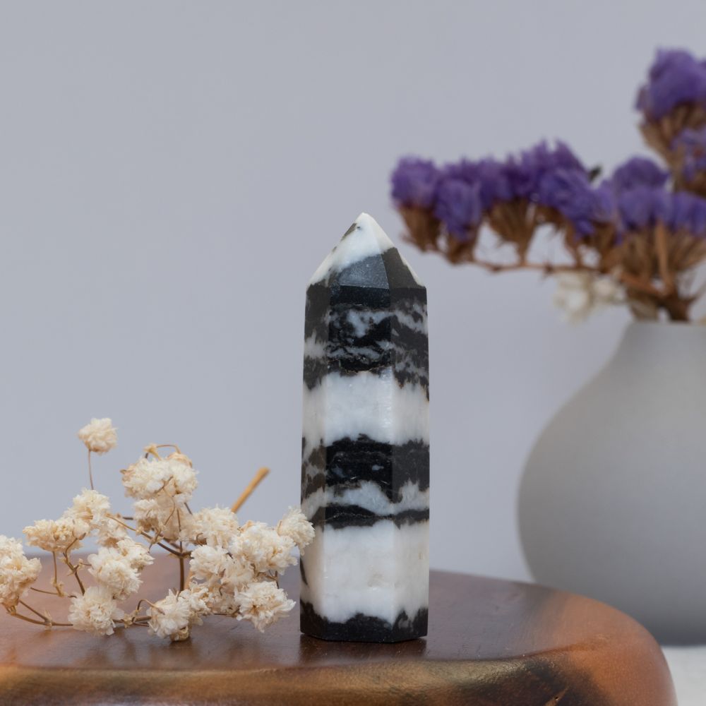 Black and white crystal tower on a wooden surface with flowers in the background