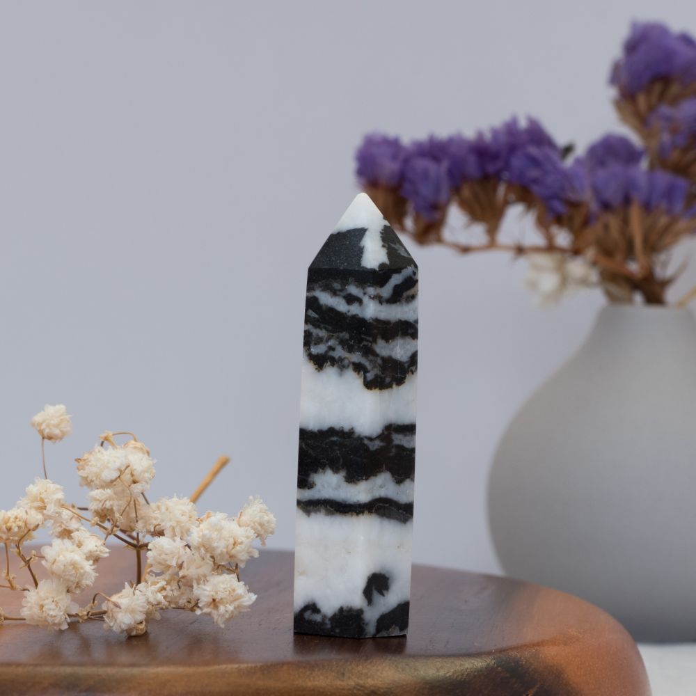 Black and white striped zebra jasper tower with decorative flowers on a wooden surface