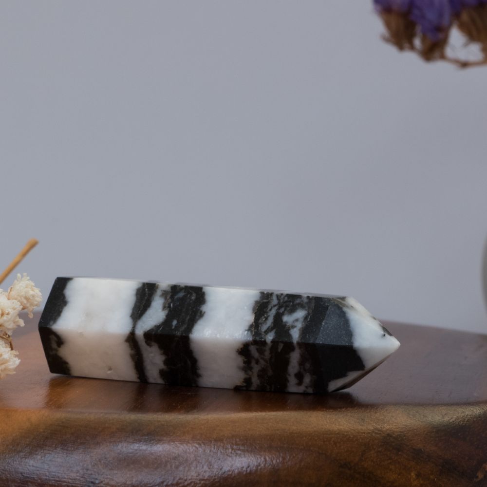 Black and white striped zebra jasper crystal on a wooden surface with a blurred background