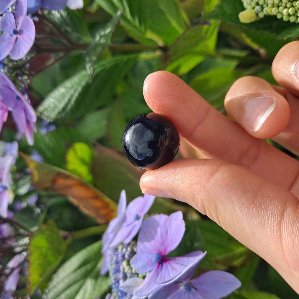 Dumi's Crystals | Black Obsidian Mini Sphere (20mm) | A close-up view of a captivating Black Obsidian Mini Sphere, showcasing its deep, glossy sheen. This 20mm sphere offers a powerful shield of protection against negativity while promoting inner healing, growth, and self-discovery.