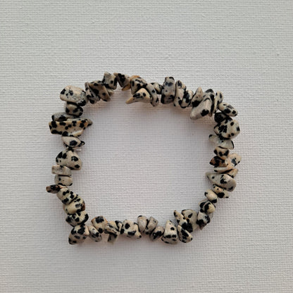 Dumi's Crystals | Dalmatian Jasper Chip Stretch Bracelet (7 Inch) | Close-up of a handcrafted bracelet featuring genuine Dalmatian Jasper chips with their characteristic black spots on a creamy beige background. Dalmatian Jasper is a unique type of Jasper, known for its playful energy and grounding protection.