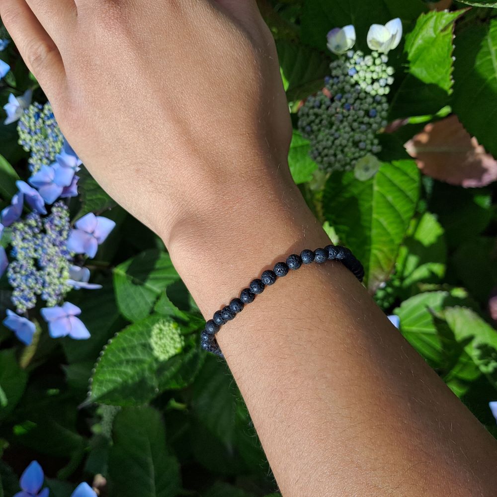 Dumi's Crystals | Lava Stone Stretch Bracelet (4mm) | Showcasing the sleek black beauty of 4mm Lava Stone beads on a wrist. This bracelet offers grounding energy, aromatherapy benefits, and a stylish touch.