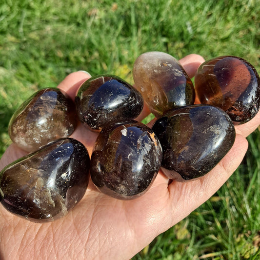 Dumi's Crystals | Smoky Quartz Tumbled Stones (Peace & Protection) | A handful of Smoky Quartz Tumbled Stones in varying shades of smoky brown. Renowned for promoting calmness, stability & protection, hold them during meditation or carry them throughout the day to cultivate a sense of peace and shield yourself from negativity.