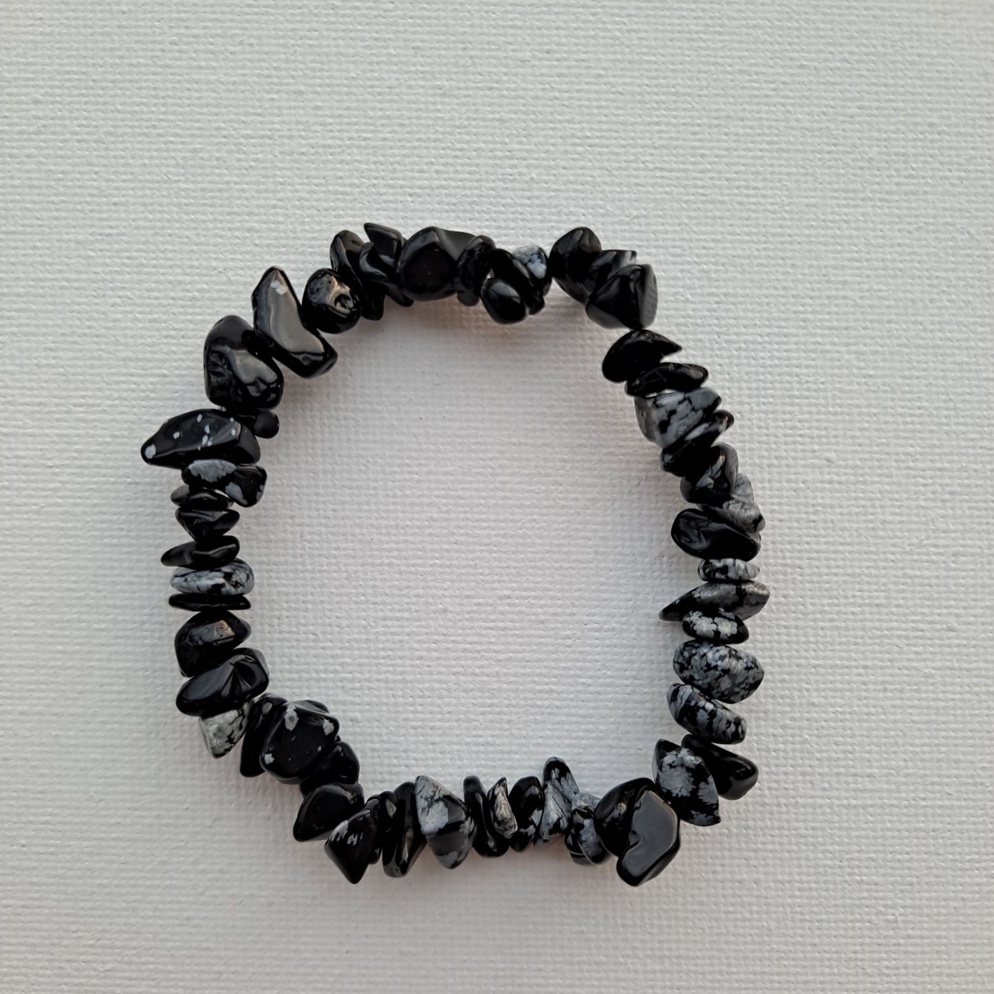 Dumi's Crystals | Snowflake Obsidian Chip Stretch Bracelet (7 Inch) | Close-up of a handcrafted bracelet featuring genuine Snowflake Obsidian chips with contrasting black and white snowflake inclusions. Snowflake Obsidian is known as the stone of transformation and is believed to promote self-discovery, emotional healing, and self-love.