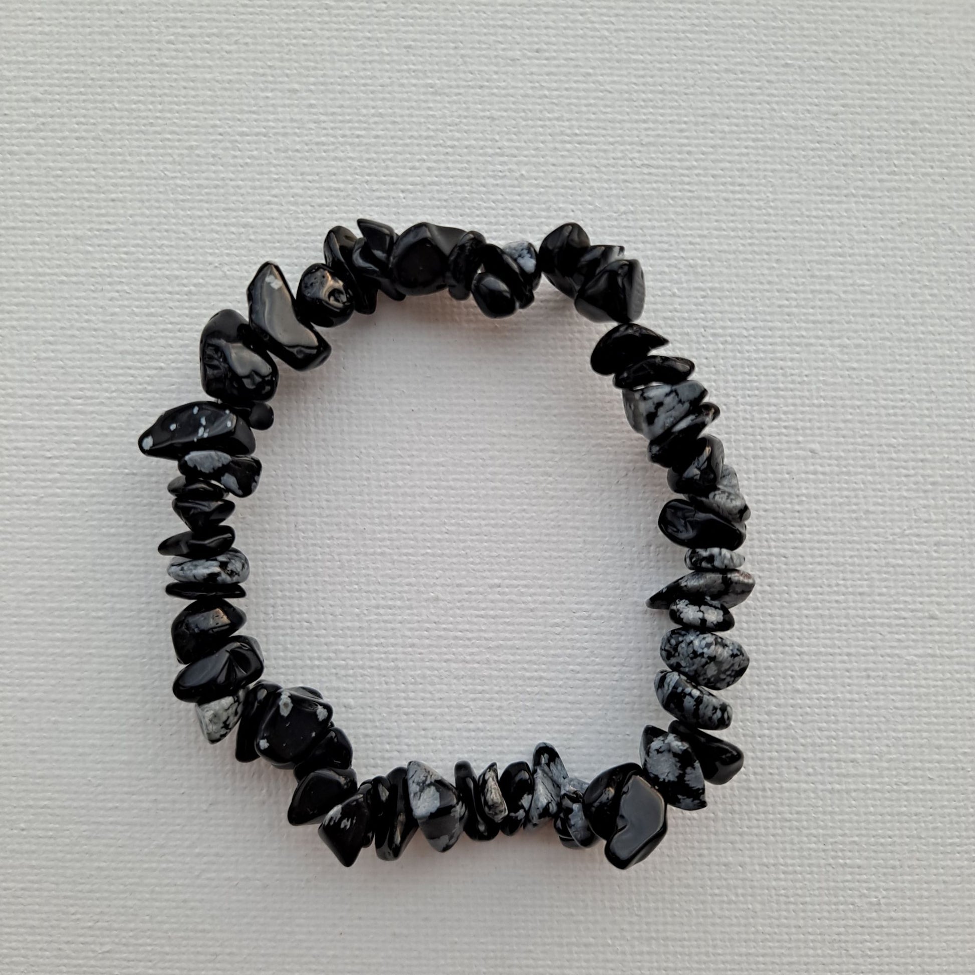 Dumi's Crystals | Snowflake Obsidian Chip Stretch Bracelet (7 Inch) | Close-up of a handcrafted bracelet featuring genuine Snowflake Obsidian chips with contrasting black and white snowflake inclusions. Snowflake Obsidian is known as the stone of transformation and is believed to promote self-discovery, emotional healing, and self-love.