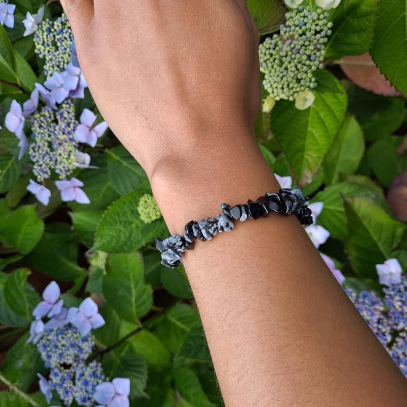  Dumi's Crystals | Snowflake Obsidian Chip Stretch Bracelet (7 Inch) | Showcasing the captivating beauty of Snowflake Obsidian chips on a wrist. This bracelet promotes self-discovery, inner reflection, emotional healing, and self-acceptance. Snowflake Obsidian, the stone of transformation, is known for its black base with contrasting white snowflake patterns.