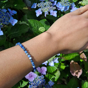 Dumi's Crystals | Sodalite Stretch Bracelet (7 Inch with 4mm Beads) | Showcasing the delicate beauty of 4mm Sodalite beads on a wrist. This bracelet promotes clear communication, self-expression, inner wisdom, and mental clarity. Sodalite, the stone of truth and communication, is known for its deep blue hues.