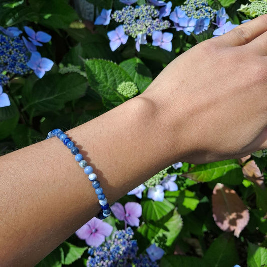 Dumi's Crystals | Sodalite Stretch Bracelet (7 Inch with 4mm Beads) | Showcasing the delicate beauty of 4mm Sodalite beads on a wrist. This bracelet promotes clear communication, self-expression, inner wisdom, and mental clarity. Sodalite, the stone of truth and communication, is known for its deep blue hues.