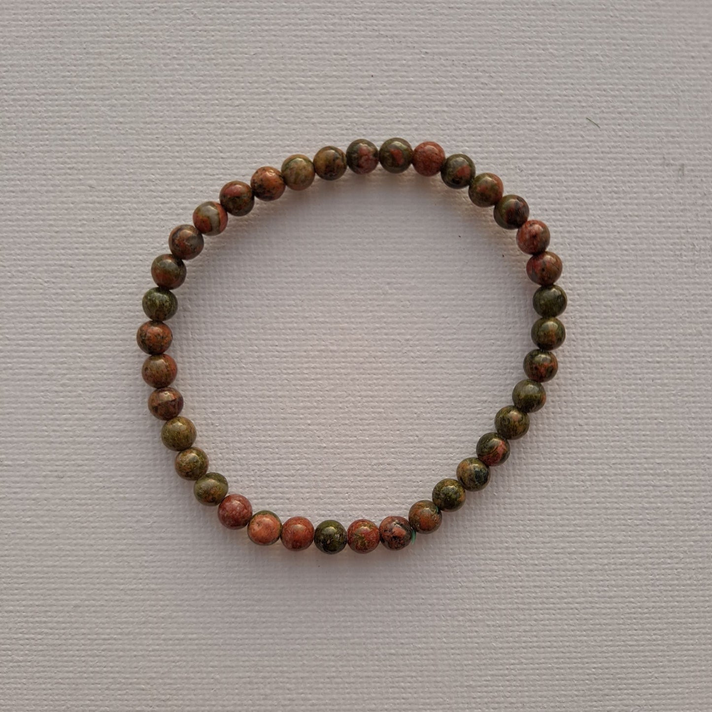 Dumi's Crystals | Unakite Stretch Bracelet (7 Inch with 4mm Beads) | Close-up of a handcrafted bracelet featuring genuine 4mm Unakite beads in calming shades of green and soft pink. Unakite is known as the stone of emotional healing and is believed to promote emotional balance, healing past wounds, self-love, and a positive outlook.