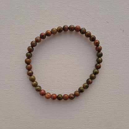 Dumi's Crystals | Unakite Stretch Bracelet (7 Inch with 4mm Beads) | Close-up of a handcrafted bracelet featuring genuine 4mm Unakite beads in calming shades of green and soft pink. Unakite is known as the stone of emotional healing and is believed to promote emotional balance, healing past wounds, self-love, and a positive outlook.